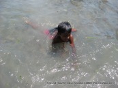 a kid swimming on a beach near rameswaram temple