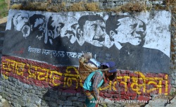 A woman walks past a Maoist mural at the entrance of Thabang village, Rolpa:   1st line: Workers of the world, unite. 2nd line: No election campaign zone!
